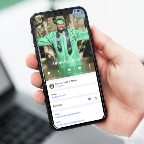 A person holds a smartphone displaying a contact profile. The screen shows a photo of a man in a green graduation cap and gown with his arms raised, and the name “Timothy Brown” appears underneath the photo. The contact details and call options are visible below the image.
